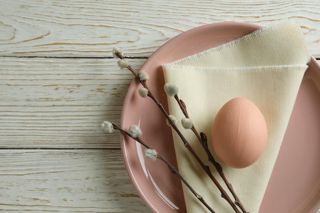 Prato com ovo, guardanapo de cozinha e amentilhos em fundo de madeira