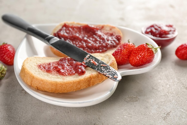 Prato com pedaços de pão e geleia de morango na mesa