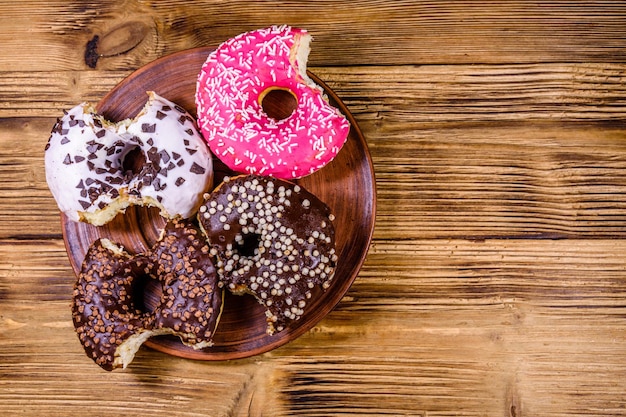 Prato com rosquinhas vitrificadas mordidas em uma mesa de madeira Vista superior