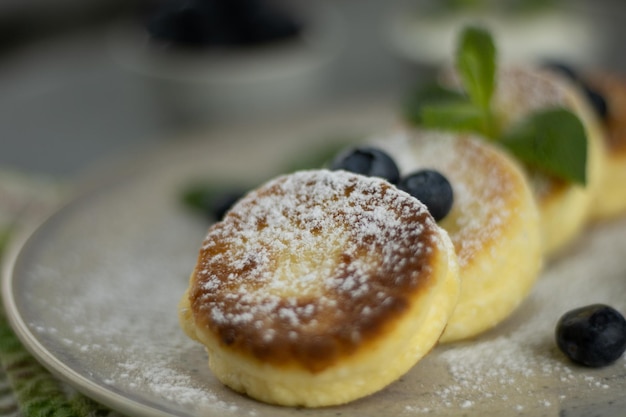 Prato com saborosas panquecas de queijo cottage e frutas na mesa