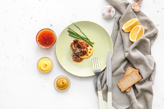 Prato com saboroso pirulito de frango em superfície clara