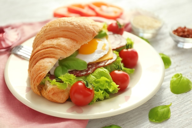 Prato com saboroso sanduíche de croissant na mesa