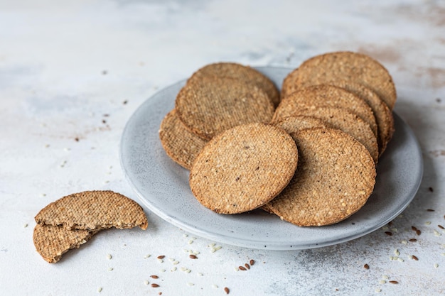 Prato com saborosos biscoitos com gergelim e sementes de linho em fundo de pedra cinza.