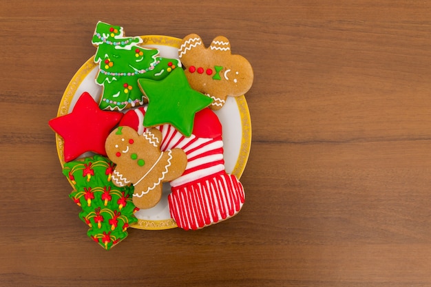 Prato com saborosos biscoitos de Natal festivos em forma de árvore de Natal, homem-biscoito, estrela e meia de Natal na mesa de madeira. Vista do topo