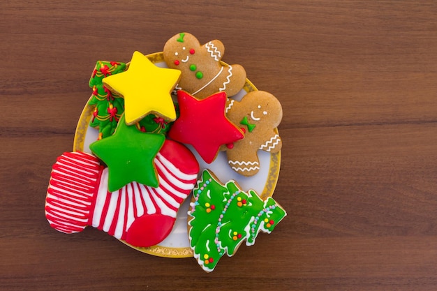 Prato com saborosos biscoitos de Natal festivos em forma de árvore de Natal, homem-biscoito, estrela e meia de Natal na mesa de madeira. Vista do topo
