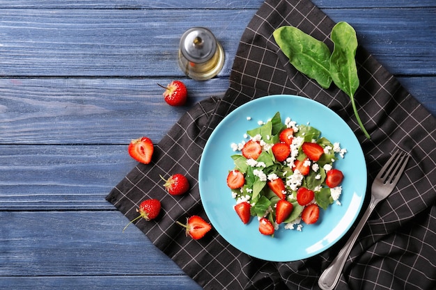 Prato com salada de morango e espinafre na mesa de madeira