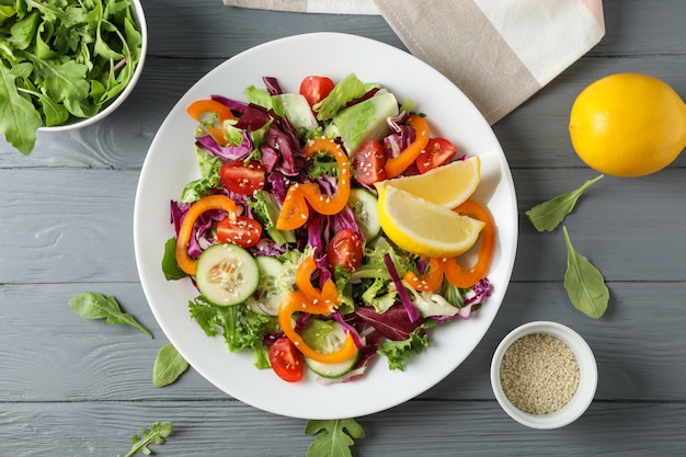 Prato com salada e ingredientes na madeira