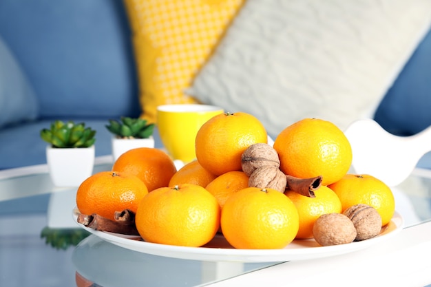 Prato com tangerinas frescas na mesa da sala, close-up