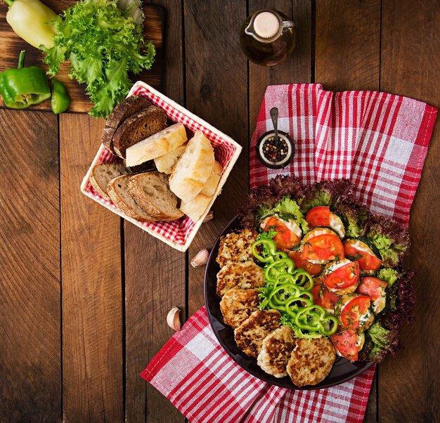 Prato com um lanche de abobrinha frita com tomates e costeletas de frango suculentas com abobrinha.