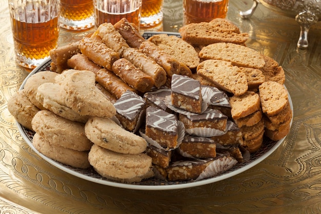 Foto prato com variedade tradicional de biscoitos festivos marroquinos de perto e chá de hortelã