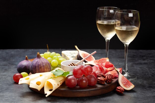 Prato de antipasto com prosciutto, queijo, figos e uvas, prato de aperitivo e vinho branco, com espaço para cópias