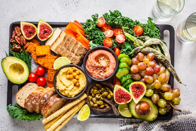 Prato de aperitivos veganos, Hummus, tofu, legumes, frutas e pão