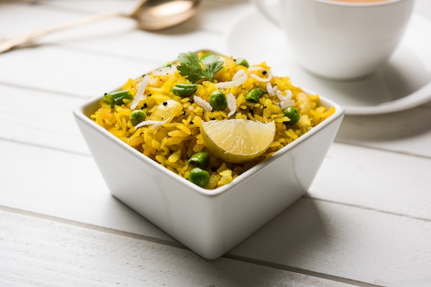 Prato de café da manhã indiano Poha também conhecido como Pohe ou Aalu poha composto de arroz batido ou arroz achatado. Os flocos de arroz são fritos levemente em óleo com temperos servidos com chá quente