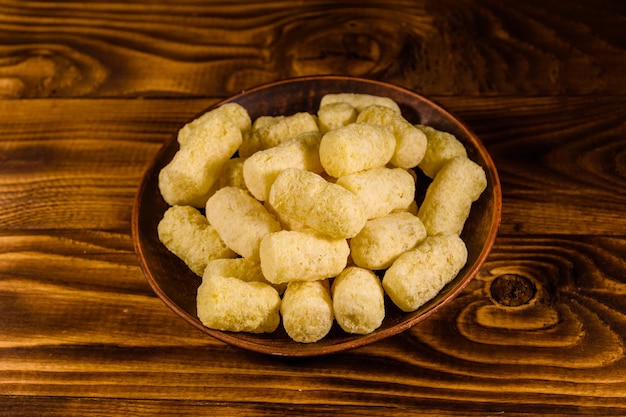 Prato de cerâmica com palitos de milho na mesa de madeira