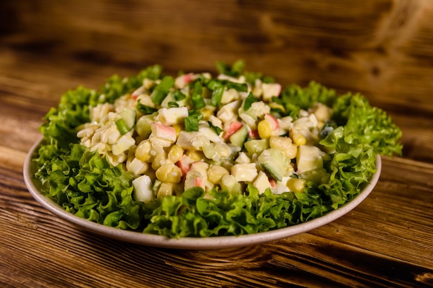 Prato de cerâmica com salada de palitos de caranguejo na mesa de madeira