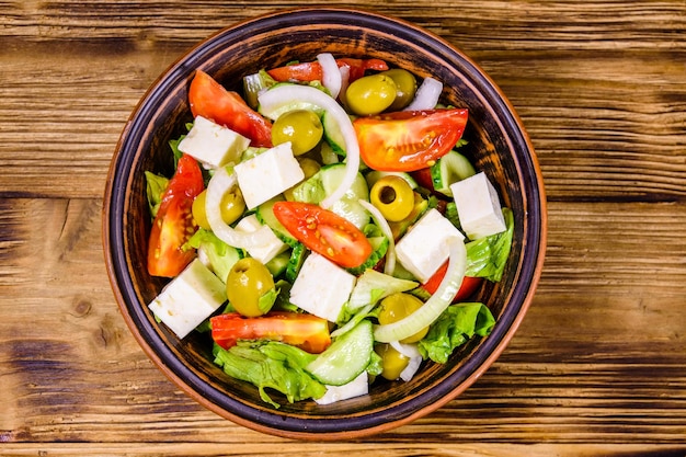 Prato de cerâmica com salada grega na mesa de madeira Vista superior