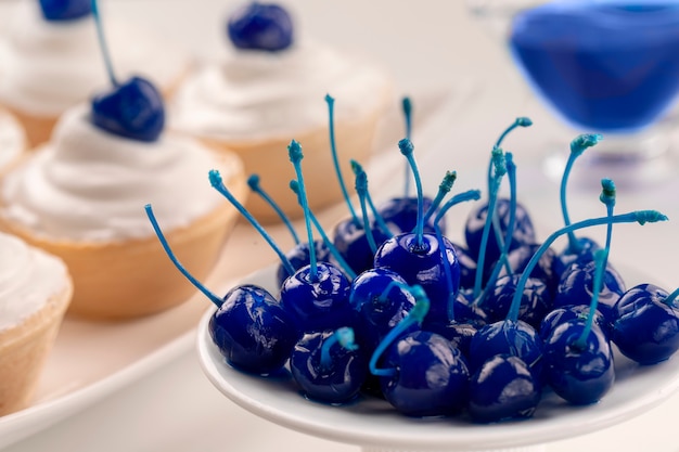 Prato de cereja em conserva azul e mini bolos com queijo creme decorado bagas de cereja azul