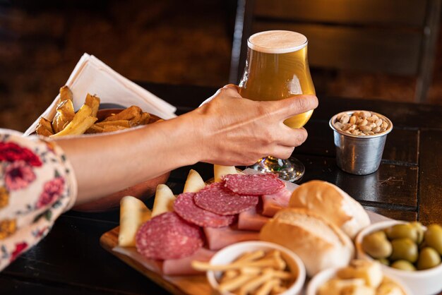 Prato de comida com batatas fritas salame e queijo com copos de cerveja