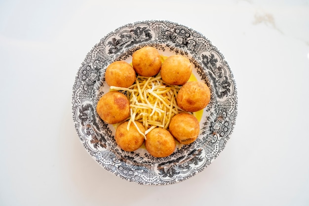 Prato de croquetes acompanhado de batatas fritas.