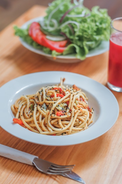 Prato de espaguete com legumes wok e salada fresca em um restaurante. fechar-se.