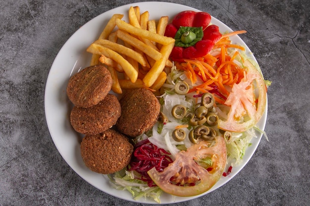 Prato de falafel com salada e batata frita servido em um fast food