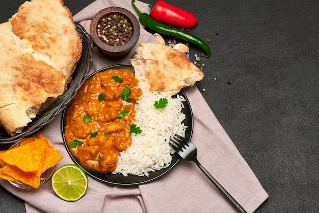 Prato de frango ao curry tradicional e arroz na mesa escura