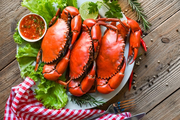 Prato de frutos do mar com ervas especiarias alecrim limão limão salada alface vegetal caranguejo fresco na chapa branca e molho de frutos do mar caranguejo cozinhar comida caranguejo cozido ou cozido no vapor vermelho na vista superior do restaurante