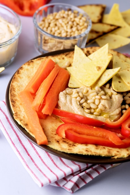 Prato de Homus Grão de Bico Dip Nuts Páprica Cenouras e Azeite Com Pita ou Chips Fundo Azul