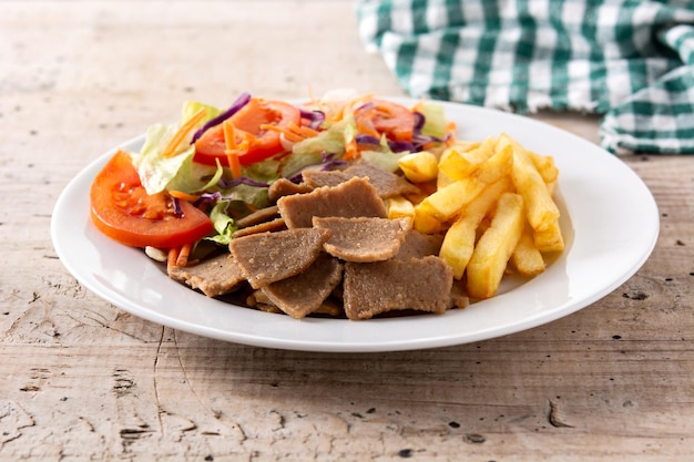 Prato de kebab, legumes e batatas fritas na mesa de madeira