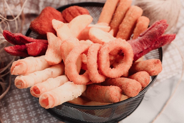 Prato de lanche delicioso, batatas fritas, anéis de cebola, rolinhos primavera ou salsichas na mesa 1