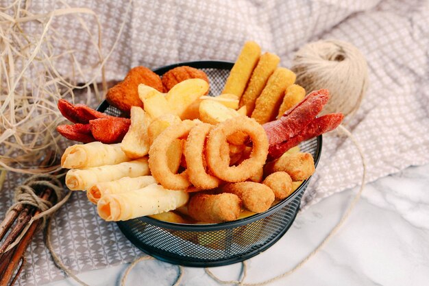 Prato de lanche delicioso, batatas fritas, anéis de cebola, rolinhos primavera ou salsichas na mesa