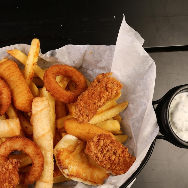 Prato de lanche delicioso, batatas fritas, anéis de cebola, rolinhos primavera ou salsichas na mesa