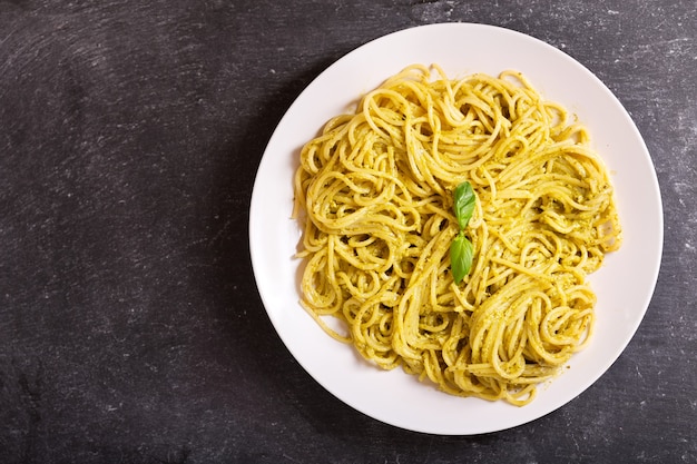 Prato de macarrão com molho pesto na mesa escura