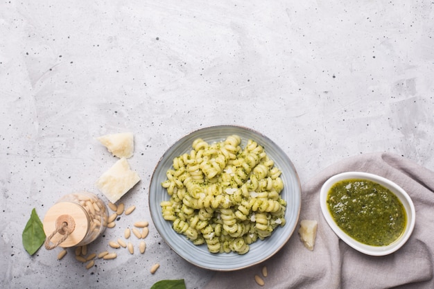 Prato de macarrão fusilli com molho pesto em fundo cinza de concreto