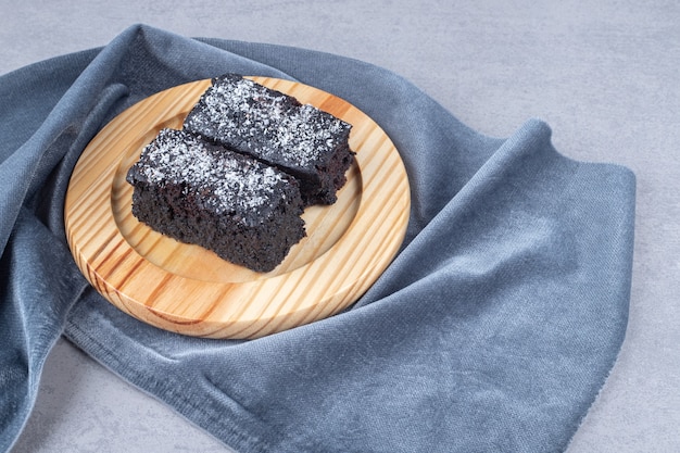 prato de madeira com fatias de bolo de brownie na mesa de pedra