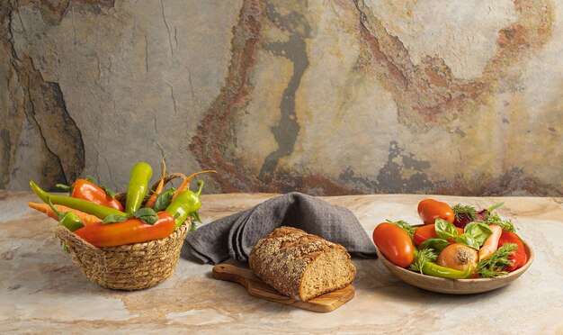 Prato de madeira tradicional e cesta com legumes frescos pimenta verde tomate cebola cenoura pepino manjericão pão de endro têxtil na vista superior de fundo marrom vintage