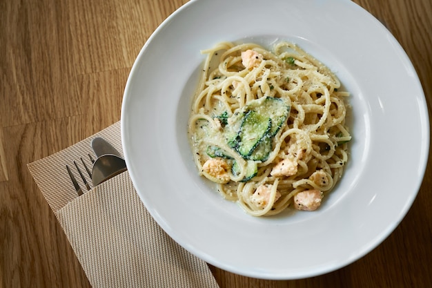 Prato de massa italiana fettuccine em molho cremoso com salmão e abobrinha na mesa