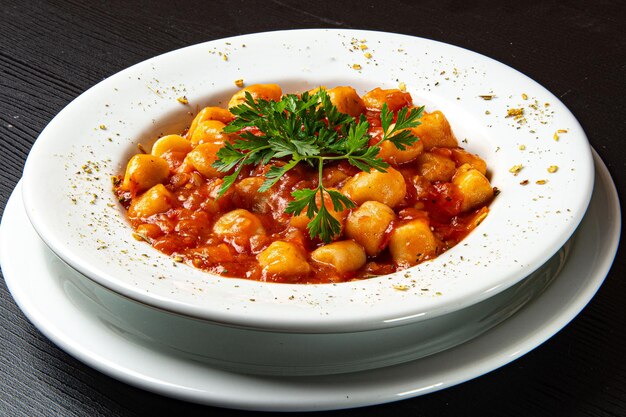 Prato de nhoque com molho de tomate e salsa na mesa de madeira rústica