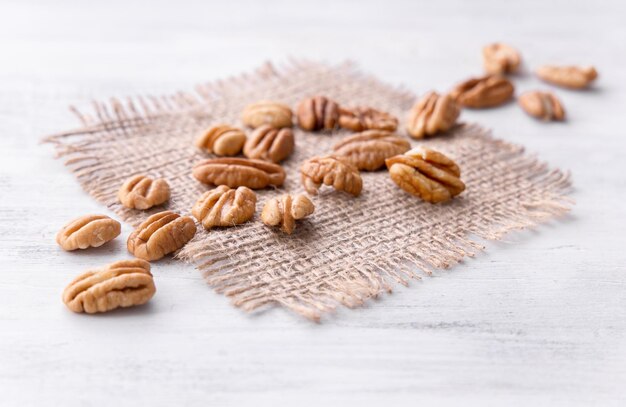 Prato de nozes pecan secas no pedaço de serapilheira no catálogo de fundo de madeira branco