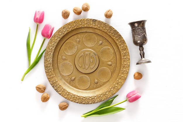 Prato de ouro para Seder Pesach feriado da Páscoa judaica com as inscrições ovo shankbone ervas amargas alface charoset salsa Garrafa de vinho tulipa flores vidro de prata nozes