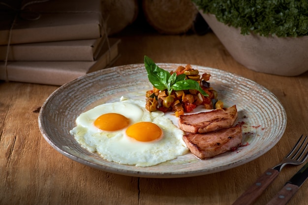 Prato de ovos fritos com bacon e legumes na mesa de madeira. Café da manhã inglês na mesa