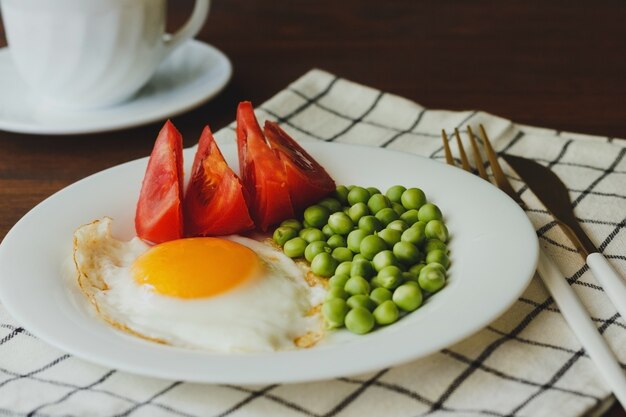 Prato de ovos fritos com legumes na mesa de madeira