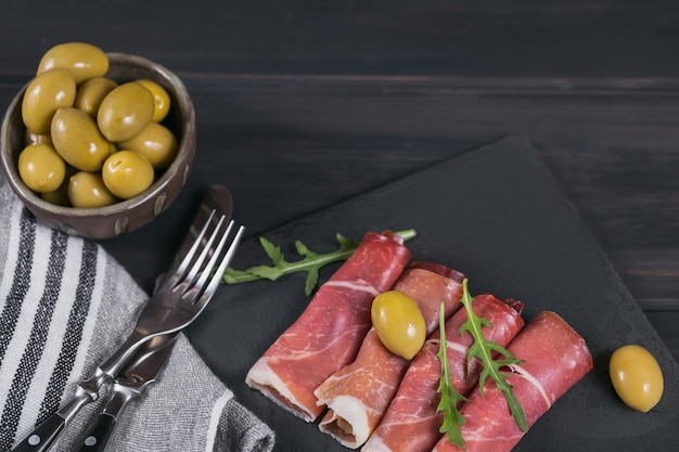 prato de pedra preta com fatias de presunto ou jamon serrano espanhol ou prosciutto crudo italiano