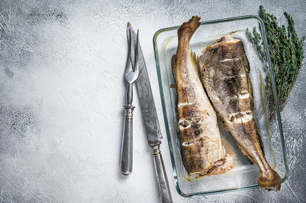 Prato de peixe - bacalhau assado com ervas na assadeira. Vista do topo.