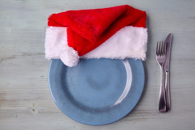 Prato de prato azul vazio com um boné de natal e talheres