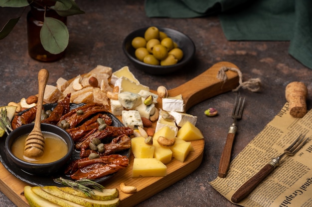 Prato de queijo com diferentes queijos, tomates secos, nozes, mel e tâmaras na placa de madeira rústica.