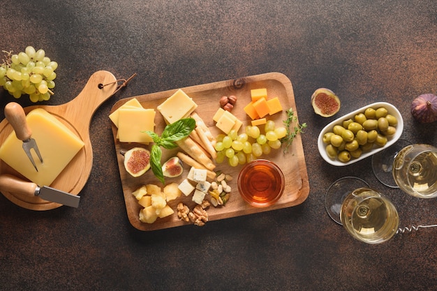 Prato de queijo com uvas, nozes, figos em fundo marrom, vista superior