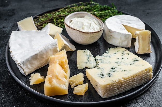 Prato de queijo francês. Camembert, Brie, Gorgonzola e queijo cremoso azul. Fundo preto. Vista do topo.