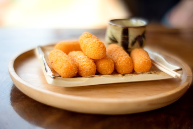 Prato de queijo frito com molho na tigela de madeira