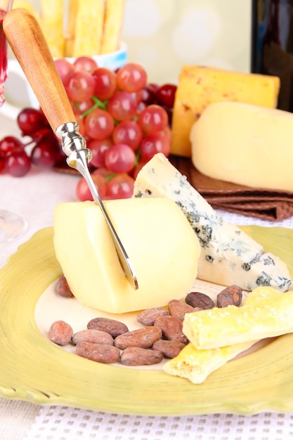 Prato de queijo variado uva e copo de vinho na mesa sobre fundo claro